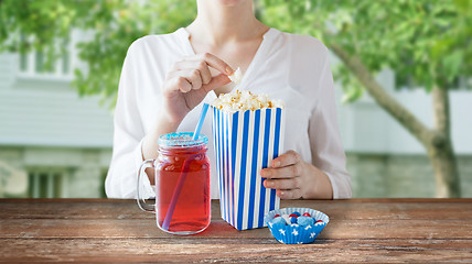 Image showing woman eating popcorn with drink in glass mason jar