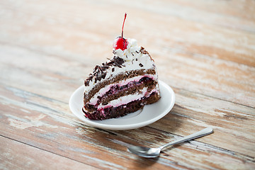 Image showing piece of cherry chocolate cake on wooden table