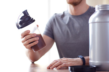 Image showing close up of man with protein shake bottle and jar