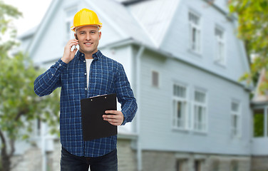 Image showing smiling builder in helmet calling on smartphone