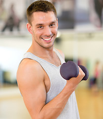 Image showing smiling man with dumbbell in gym