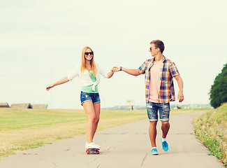 Image showing smiling couple with skateboard outdoors