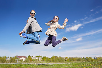 Image showing happy little girls jumping high outdoors