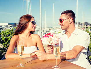 Image showing smiling couple with bunch and champagne at cafe