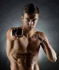 Image showing young man on fighting stand over black background