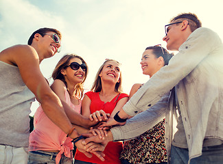 Image showing group of smiling friends with hands on top in city