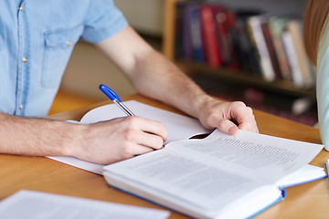 Image showing close up of student hands writing to notebook