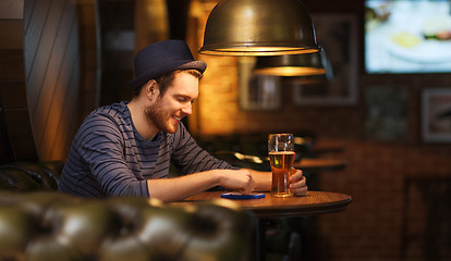 Image showing man with smartphone and beer texting at bar