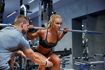 Image showing man and woman with bar flexing muscles in gym