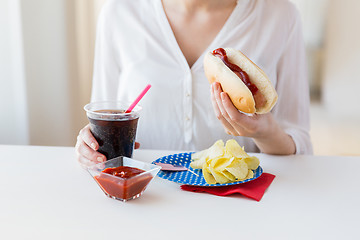 Image showing close up of woman eating hot dog with coca cola