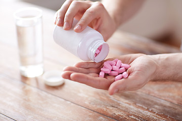 Image showing close up of man pouring pills from jar to hand