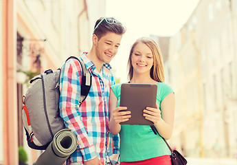 Image showing smiling couple with tablet pc and backpack in city