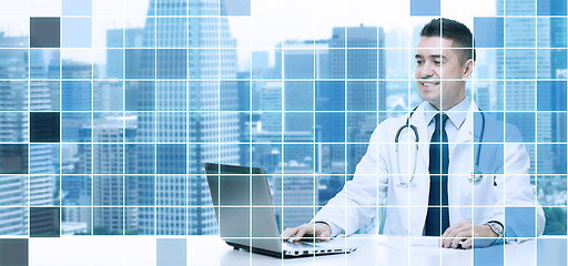 Image showing smiling male doctor with laptop sitting at table