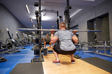 Image showing young man flexing muscles with bar in gym