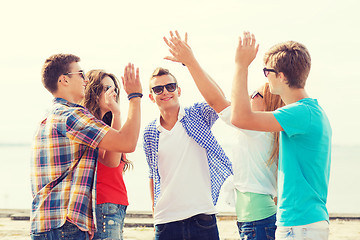 Image showing group of smiling friends making high five outdoors
