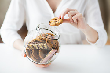 Image showing close up of hands with chocolate cookies in jar