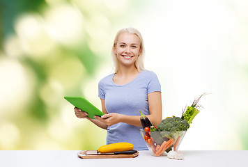 Image showing smiling woman with tablet pc cooking vegetables
