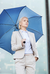 Image showing young serious businesswoman with umbrella outdoors