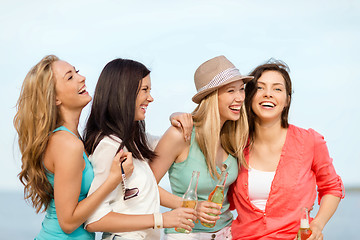 Image showing smiling girls with drinks on the beach