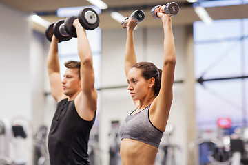 Image showing smiling man and woman with dumbbells in gym