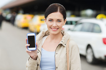 Image showing smiling woman showing smartphone over taxi in city