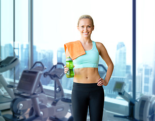 Image showing happy woman with bottle of water and towel in gym