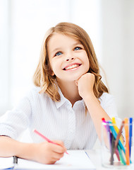 Image showing smiling little student girl drawing at school