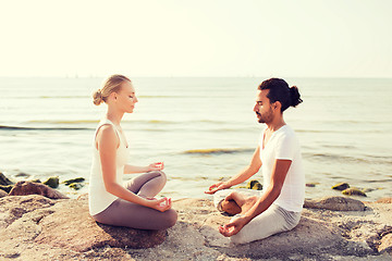 Image showing smiling couple making yoga exercises outdoors