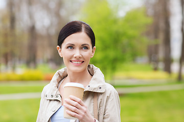 Image showing smiling woman drinking coffee in park