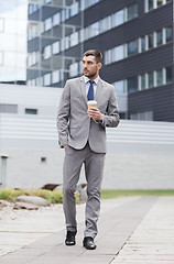 Image showing young serious businessman with paper cup outdoors