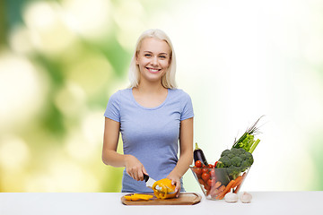 Image showing smiling young woman chopping vegetables at home