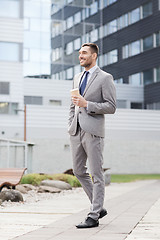 Image showing young serious businessman with paper cup outdoors