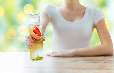 Image showing close up of woman with fruit water in glass bottle