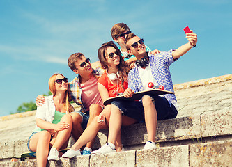 Image showing group of smiling friends with smartphone outdoors