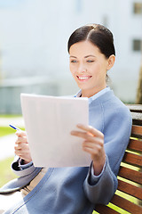 Image showing smiling businesswoman reading papers outdoors