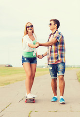 Image showing smiling couple with skateboard outdoors