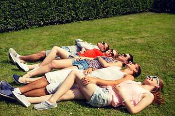 Image showing group of smiling friends lying on grass outdoors