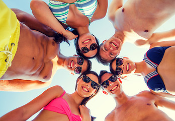 Image showing smiling friends in circle on summer beach