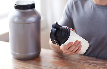 Image showing close up of man with protein shake bottle and jar