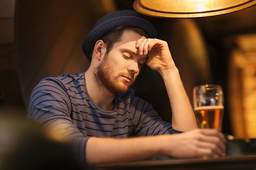 Image showing unhappy lonely man drinking beer at bar or pub