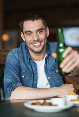 Image showing happy young man drinking beer at bar or pub