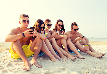 Image showing group of friends with smartphones on beach