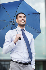 Image showing young smiling businessman with umbrella outdoors