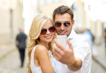 Image showing smiling couple with smartphone in the city