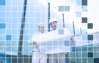 Image showing smiling business people in helmets with blueprint