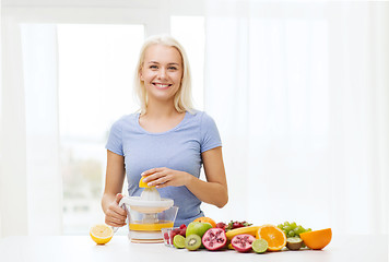 Image showing smiling woman squeezing fruit juice at home