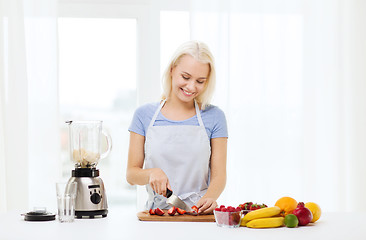 Image showing smiling woman with blender preparing shake at home