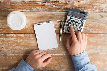 Image showing close up of hands with calculator and notebook