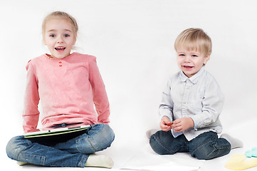 Image showing Girl uses a tablet and boy playing with chalk