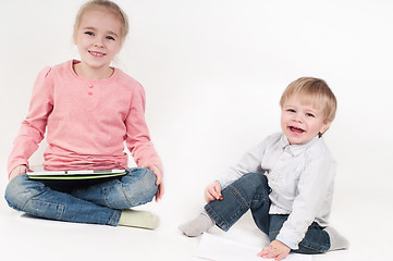 Image showing Happy girl uses tablet and boy playing with chalk